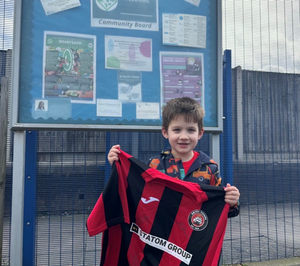 A child from Northumberland Heath Primary School holds up an Erith Town football shirt.